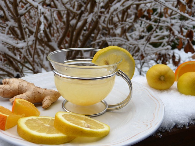a cup of lemon tea on a plate with fresh lemons and ginger during the winter